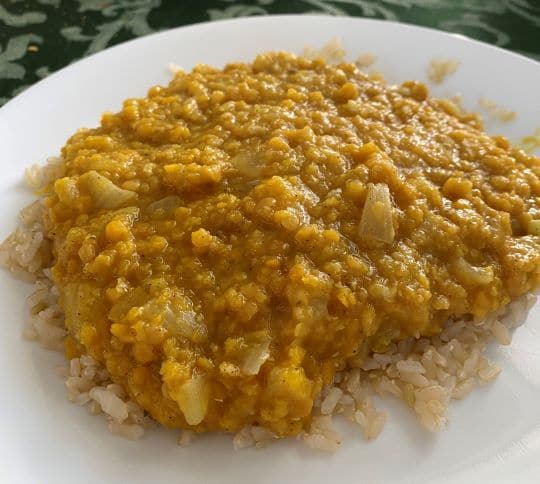 Picture of Dahl (Indian lentils) on a plate with some rice on the bottom.