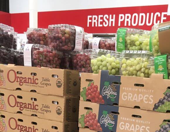 Picture of grapes with a sign sayingfresh produce in the background.