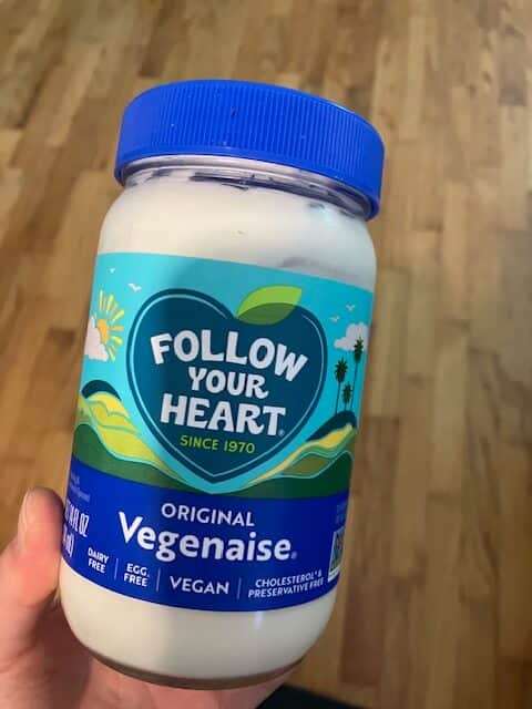 picture of a hand holding follow your heart vegenaise