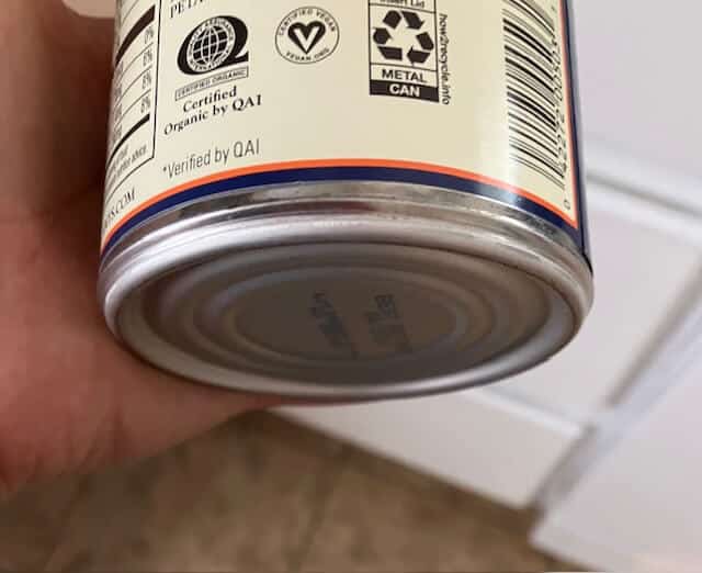 picture of a hand holding a can that has a certified vegan symbol on it